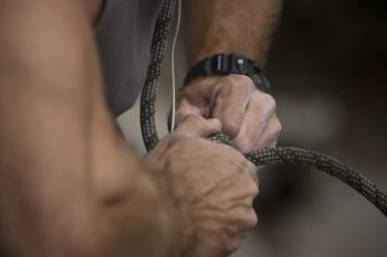 Man tying rope harness to waist.