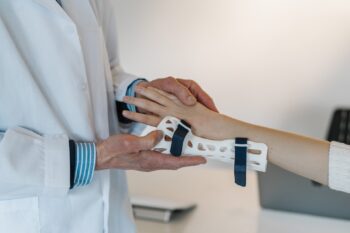 Doctor fastening a wrist brace onto a patients arm.